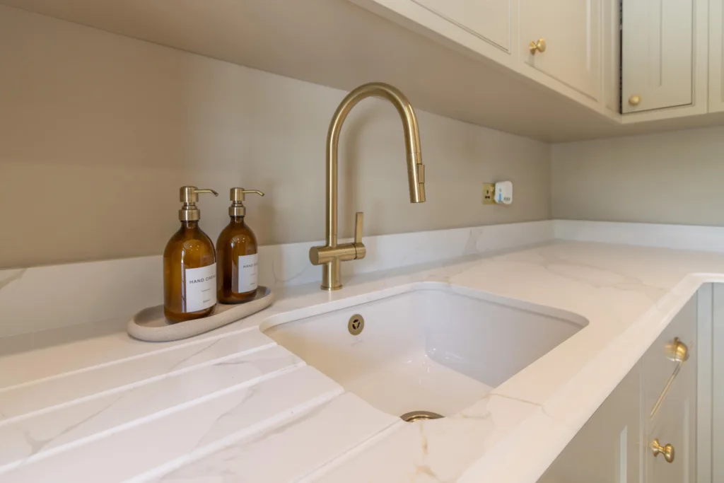 Bespoke kitchen worktop in veined quartz with an undermount sink and a brushed brass mixer tap