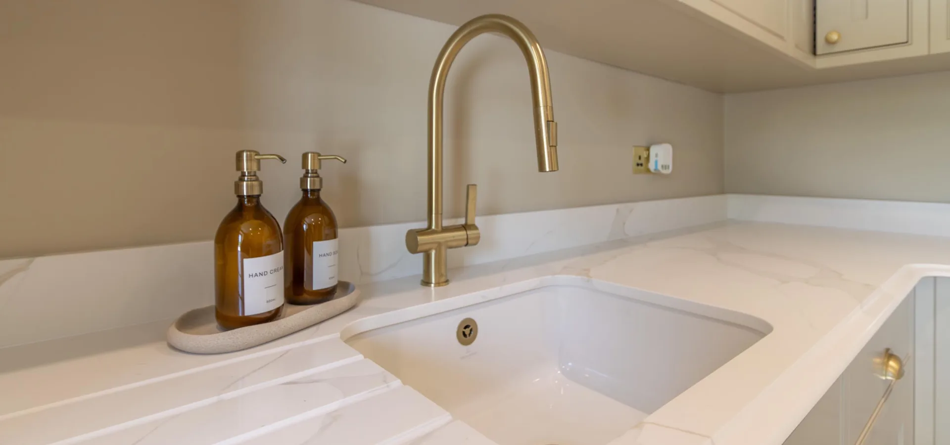 Bespoke kitchen worktop in veined quartz with an undermount sink and a brushed brass mixer tap