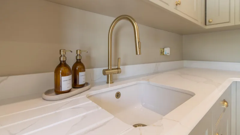 Bespoke kitchen worktop in veined quartz with an undermount sink and a brushed brass mixer tap