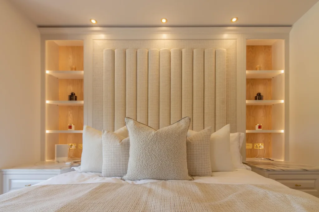 Fitted bedroom with an upholstered fluted headboard and LED-lit alcove shelving either side of the bed
