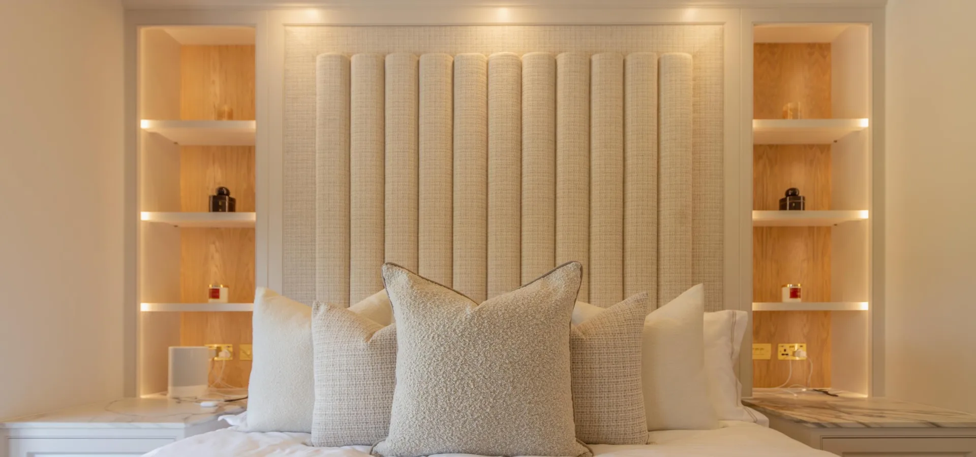 Fitted bedroom with an upholstered fluted headboard and LED-lit alcove shelving either side of the bed