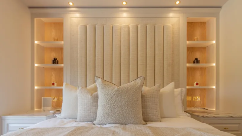 Fitted bedroom with an upholstered fluted headboard and LED-lit alcove shelving either side of the bed
