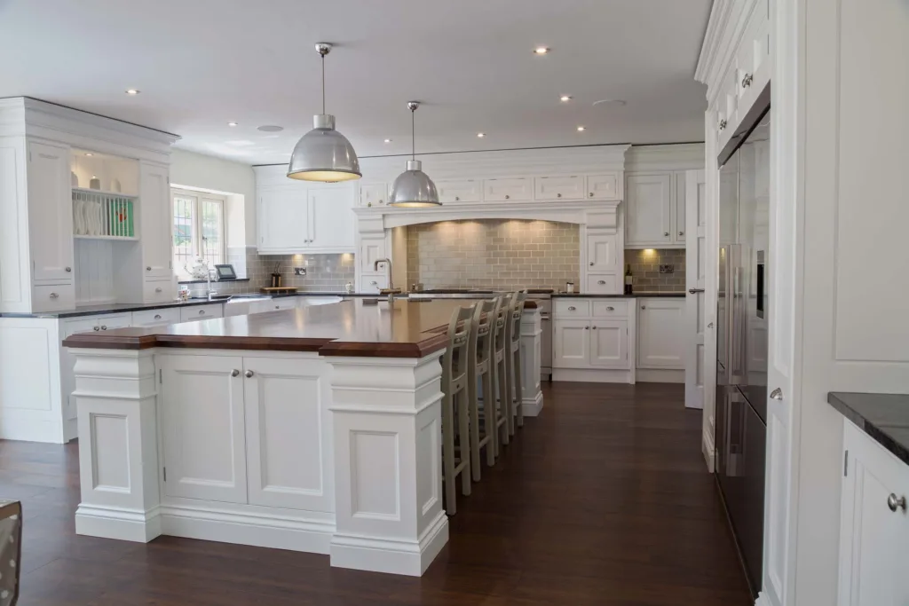 Large classic white kitchen with a long central island, pendant lighting and a dark timber floor