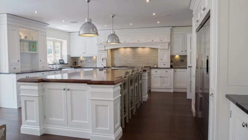 Large classic white kitchen with a long central island, pendant lighting and a dark timber floor