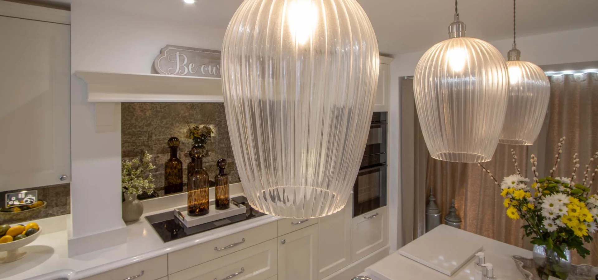 Ribbed glass pendant lights above a classic cream kitchen island