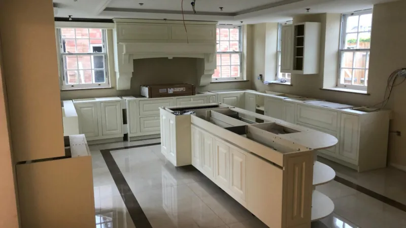 Bespoke kitchen part-way through installation, with the island and cabinetry in place before worktops are fitted